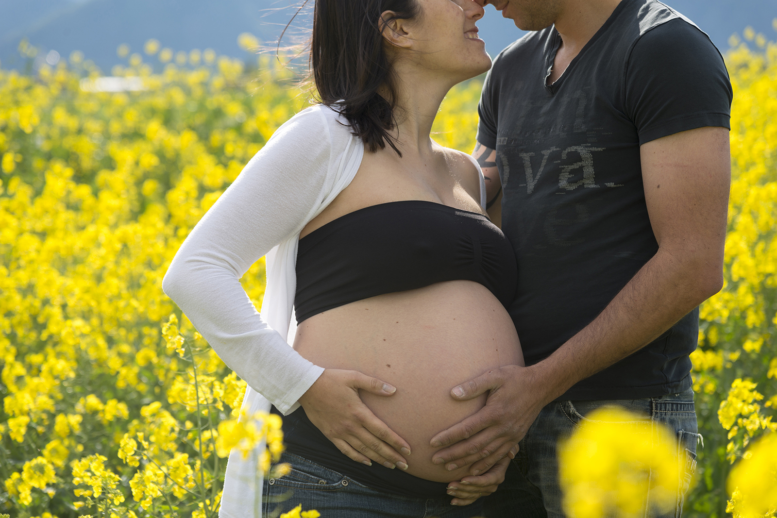 couple femme enceinte dans des champs de colza