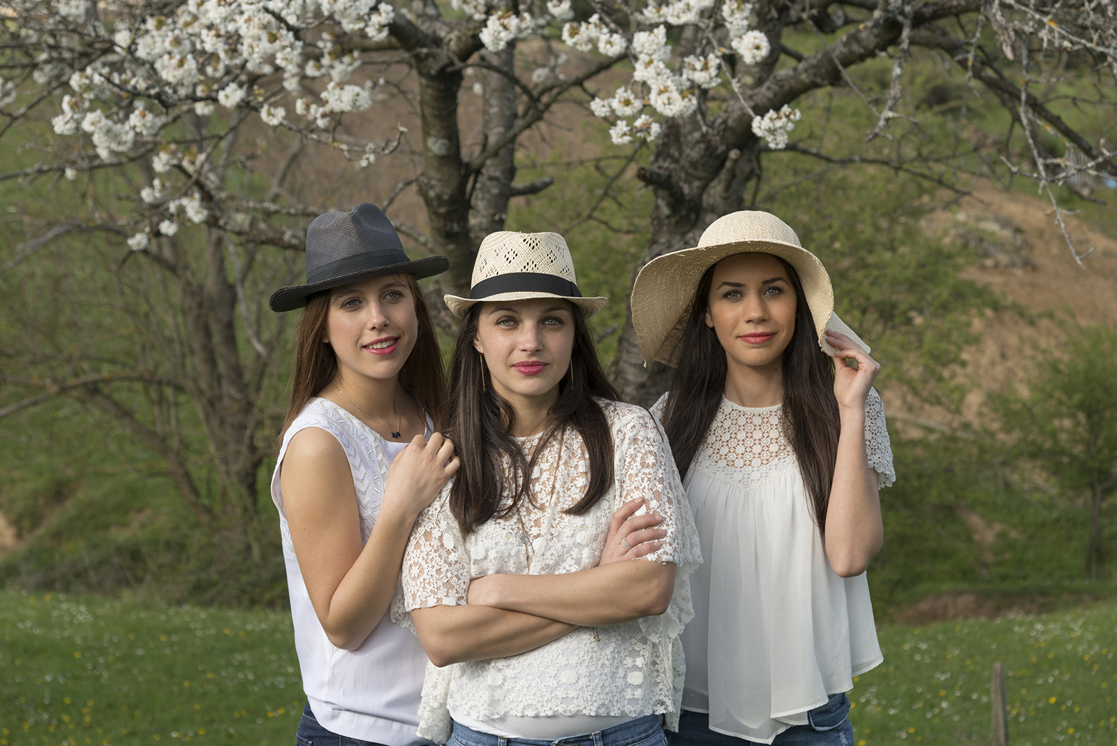 Portrait de trois jeunes femmes vetues de blanc en exterieur devant cerisier en fleur