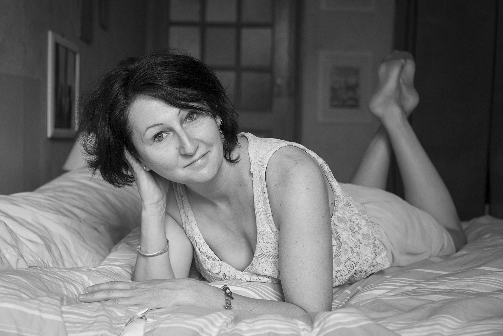 Photo noir et blanc de femme sur son lit à plat ventre