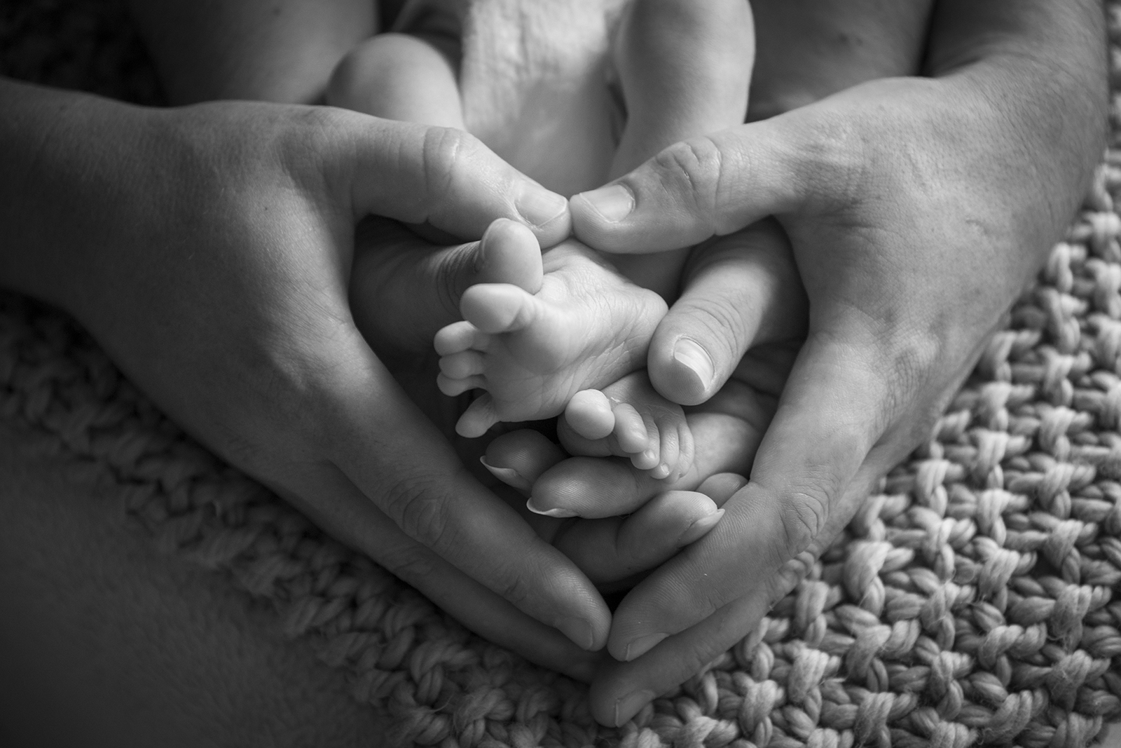 pieds de bébé et mains des parents photo en noir et blanc