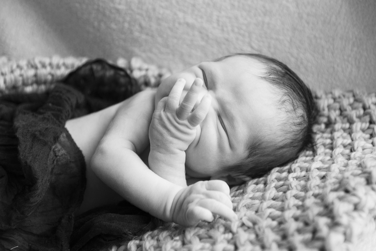 Photo de bébé en noir et blanc avec unmain devant le visage